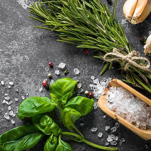 Basilic, romarin, gousses d'ail et une cuillère en bois avec du sel