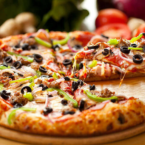 Pizza au jambon, olives et poivrons sur planche en bois